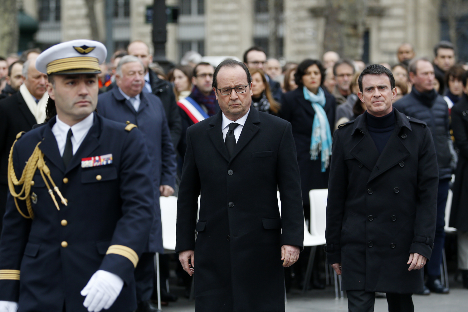 French President Francois Hollande (C) and French Prime Minister Manuel Valls (R) attend a remembrance rally at Place de la Republique (Republic square) on January 10, 2016 to mark a year since 1.6 million people thronged the French capital in a show of unity after attacks on the Charlie Hebdo newspaper and a Jewish supermarket. Just as it was last year, the vast Place de la Republique will be the focus of the gathering as people reiterate their support for freedom of expression and remember the other victims of what would become a year of jihadist outrages in France, culminating in the November 13 coordinated shootings and suicide bombings that killed 130 people and were claimed by the Islamic State (IS) group. / AFP / POOL / YOAN VALAT