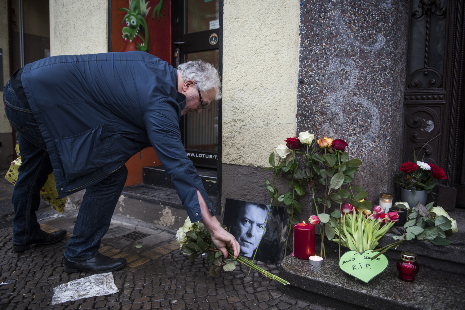 David-Bowie-fan Dirk Turnage puts down a tribute to British rock legend David Bowie outside his former home in Berlin's Hauptstrasse 155 on January 11, 2016. British rock music legend David Bowie has died after a long battle with cancer, his official Twitter and Facebook accounts said. / AFP / ODD ANDERSEN