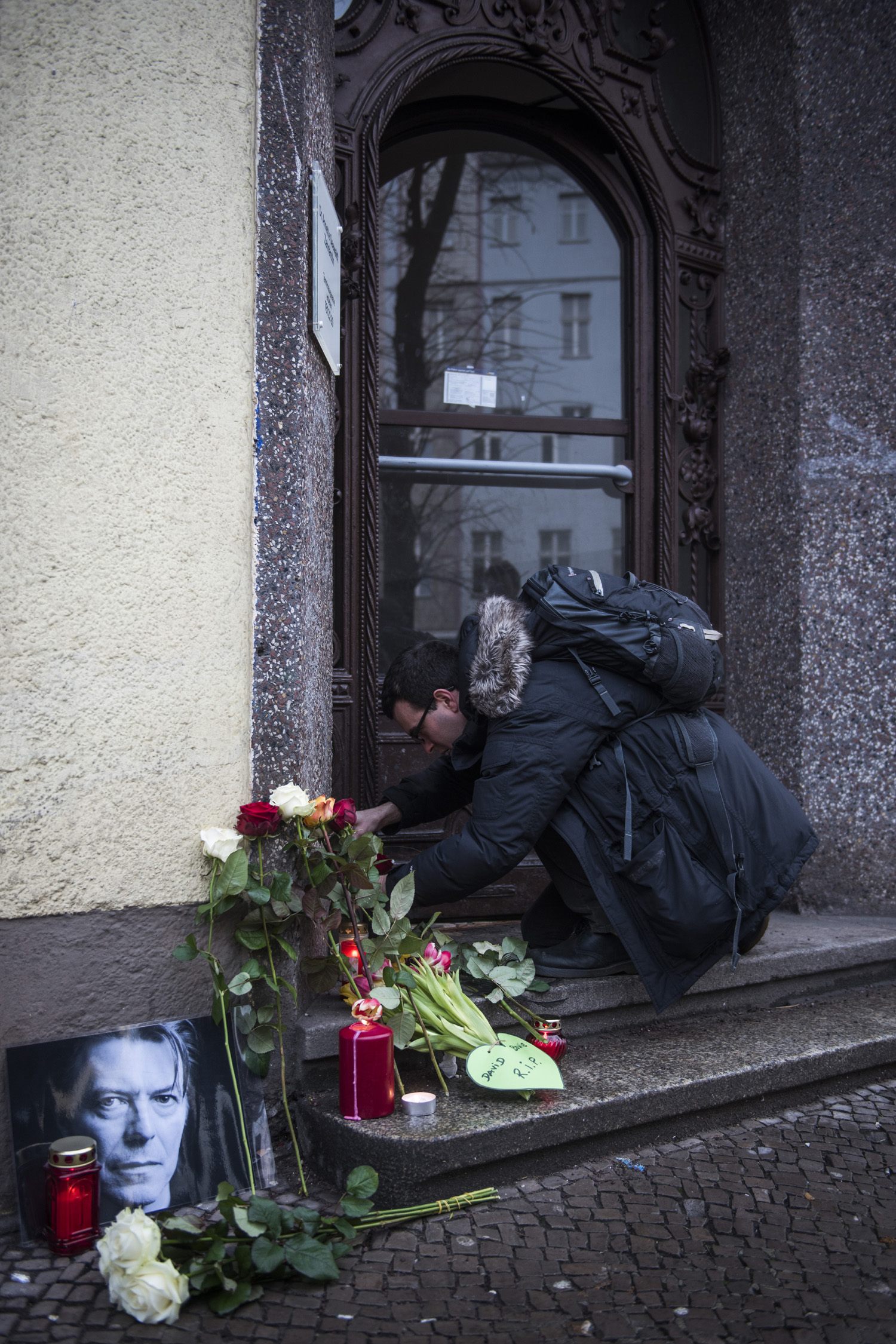 David-Bowie-fan Jamie Young puts down a tribute to British rock legend David Bowie outside his former home in Berlin's Hauptstrasse 155 on January 11, 2016. British rock music legend David Bowie has died after a long battle with cancer, his official Twitter and Facebook accounts said. / AFP / ODD ANDERSEN