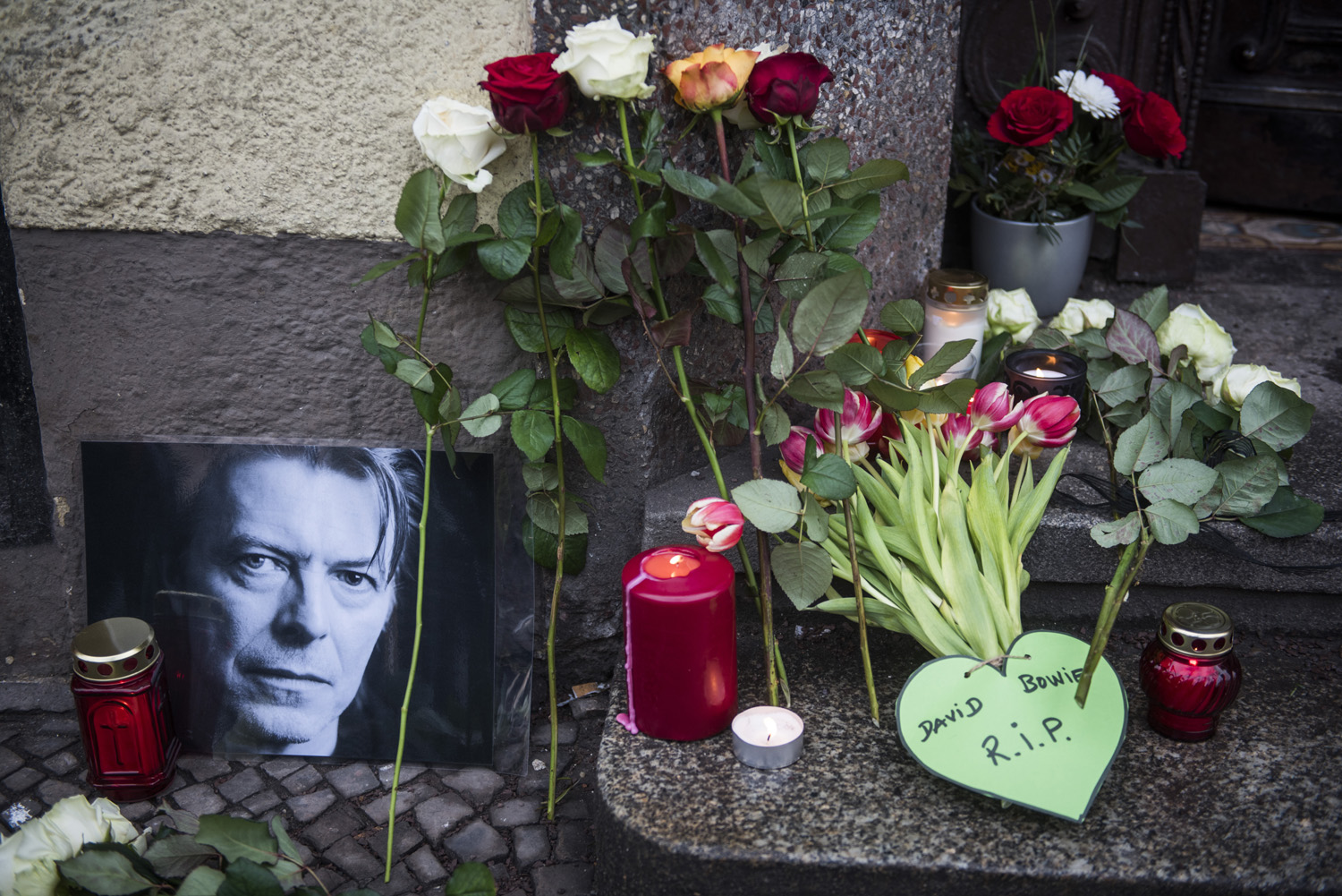 Tributes to British rock legend David Bowie are seen outside his former home in Berlin's Hauptstrasse 155 on January 11, 2016. British rock music legend David Bowie has died after a long battle with cancer, his official Twitter and Facebook accounts said. / AFP / ODD ANDERSEN