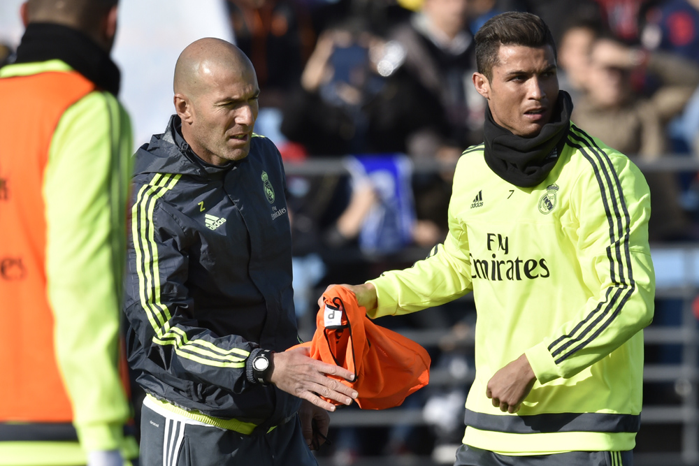 Real Madrid's Portuguese forward Cristiano Ronaldo (R) gives a bib to Real Madrid's new French coach Zinedine Zidane during his first training session as coach of Real Madrid at the Alfredo di Stefano stadium in Valdebebas, on the outskirts of Madrid, on January 5, 2016. Real Madrid legend Zinedine Zidane promised to put his "heart and soul" into managing the Spanish giants after he was sensationally named as coach following Rafael Benitez's unceremonious sacking. AFP PHOTO/ GERARD JULIEN / AFP / GERARD JULIEN
