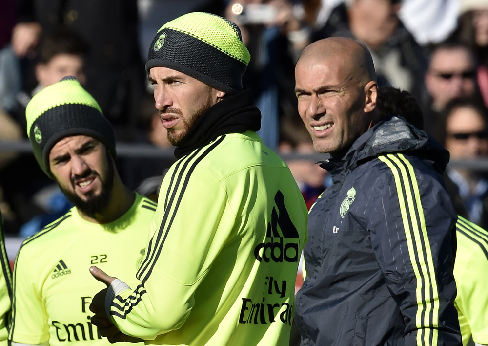Real Madrid's new French coach Zinedine Zidane (R) looks on past Real Madrid's defender Sergio Ramos (C) during his first training session as coach of Real Madrid at the Alfredo di Stefano stadium in Valdebebas, on the outskirts of Madrid, on January 5, 2016. Real Madrid legend Zinedine Zidane promised to put his "heart and soul" into managing the Spanish giants after he was sensationally named as coach following Rafael Benitez's unceremonious sacking. AFP PHOTO/ GERARD JULIEN / AFP / GERARD JULIEN
