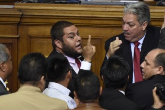 Newly elected opposition deputy Juan Requesens (C) argues with governement deputies during the new parliament's swearing-in ceremony in Caracas, on January 5, 2016. Venezuela's President Nicolas Maduro ordered the security forces to ensure the swearing-in of a new opposition-dominated legislature passes off peacefully Tuesday, after calls for rallies raised fears of unrest. AFP PHOTO/JUAN BARRETO / AFP / JUAN BARRETO