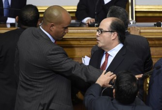 Newly elected opposition deputy Julio Borges (C) and governement deputy Hector Rodriguez (L) argue during the new parliament's swearing-in ceremony in Caracas, on January 5, 2016. Venezuela's President Nicolas Maduro ordered the security forces to ensure the swearing-in of a new opposition-dominated legislature passes off peacefully Tuesday, after calls for rallies raised fears of unrest. AFP PHOTO/JUAN BARRETO / AFP / JUAN BARRETO