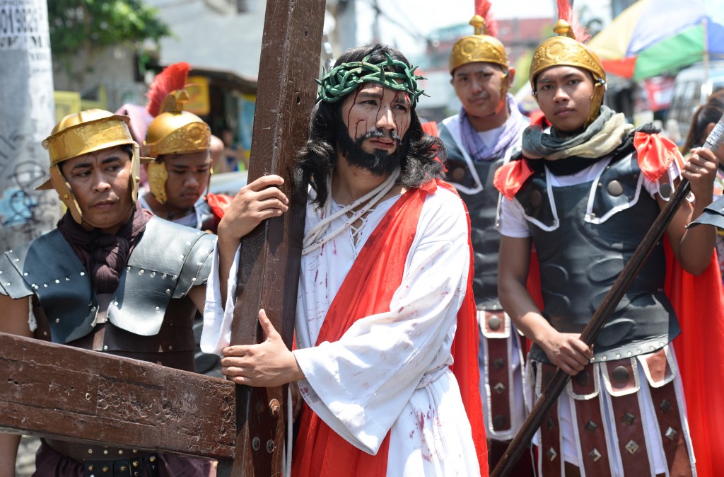 Actors playing the role of Jesus (C) and Roman soldiers (background) reenact the suffering and crucifixion of Jesus in a street play as part of Lenten observance during Holy Week in Manila on March 24, 2016, ahead of Easter. Christian believers around the world mark the Holy Week of Easter in celebration of the crucifixion and resurrection of Jesus Christ. / AFP / TED ALJIBE