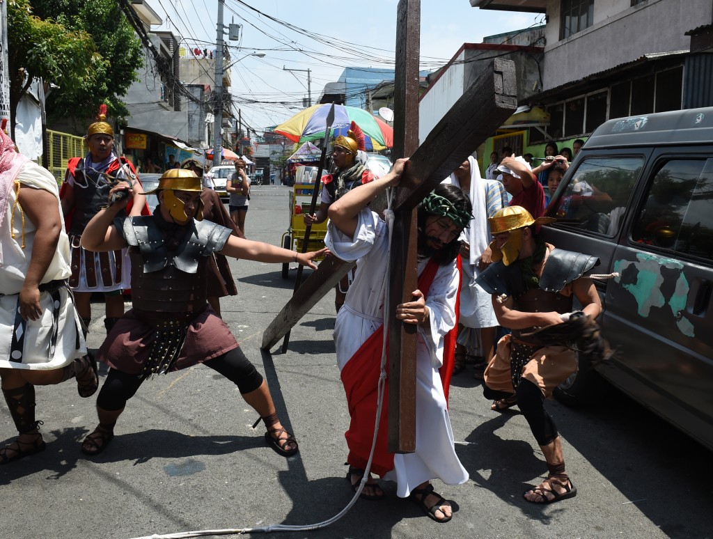 Actors playing the role of Jesus (C) and Roman soldiers (background) reenact the suffering and crucifixion of Jesus in a street play as part of Lenten observance during Holy Week in Manila on March 24, 2016, ahead of Easter. Christian believers around the world mark the Holy Week of Easter in celebration of the crucifixion and resurrection of Jesus Christ. / AFP / TED ALJIBE
