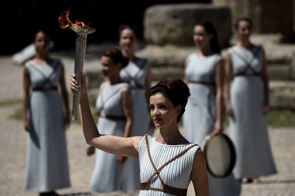 Actress Katerina Lechou acting the high pristess holds a torch with the Olympic flame at the Temple of Hera on April 20, 2016 during a dress rehearsal of the lighting ceremony of the Olympic flame in ancient Olympia, the sanctuary where the Olympic Games were born in 776 BC. / AFP PHOTO / ARIS MESSINIS