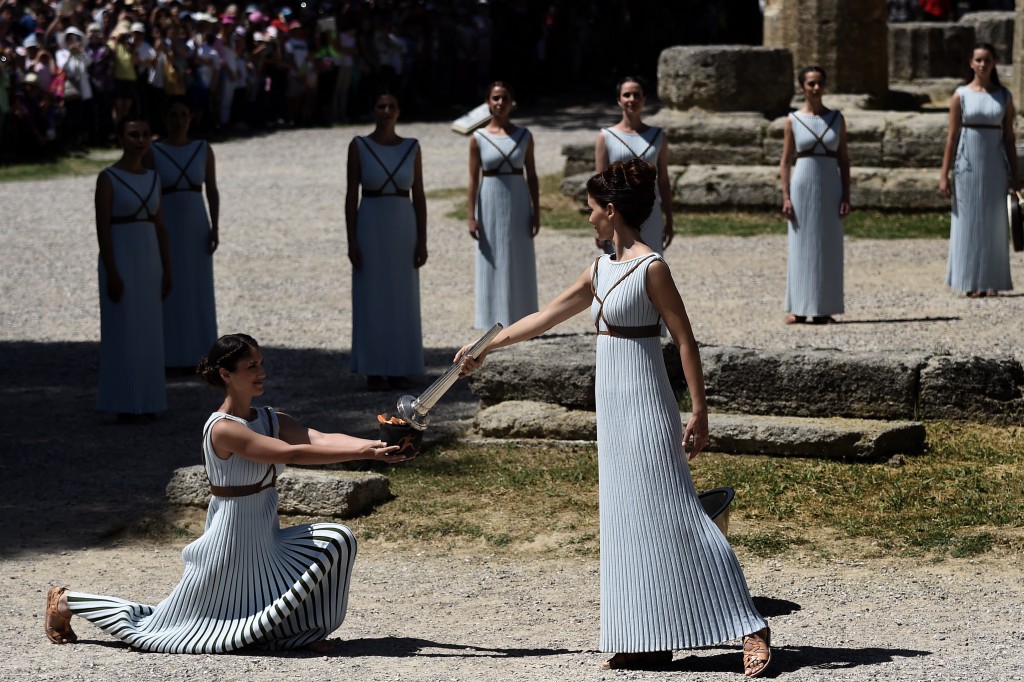 Actress Katerina Lechou (R) acting the high pristess passes the Olympic flame at the Temple of Hera on April 20, 2016 during a dress rehearsal of the lighting ceremony of the Olympic flame in ancient Olympia, the sanctuary where the Olympic Games were born in 776 BC. / AFP PHOTO / ARIS MESSINIS