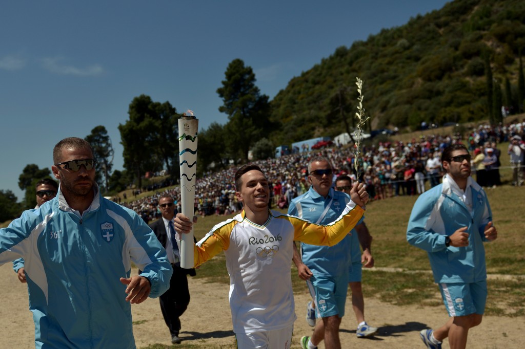 First torchbearer world champion at artistic gymnastics, Lefteris Petrounias runs with the Olympic Flame as he arrives at the Temple of Hera on April 21, 2016 during the lighting ceremony of the Olympic flame in ancient Olympia, the sanctuary where the Olympic Games were born in 776 BC. The Olympic flame was lit Thursday in an ancient temple in one country in crisis and solemnly sent off carrying international hopes that Brazil's political paralysis will not taint the Rio Games that start in barely 100 days. / AFP PHOTO / ARIS MESSINIS