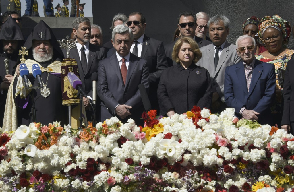 US actor George Clooney (2nd L), Armenian President Serzh Sarkisian (3rd L), his wife Rita Sarkisian and French and Armenian singer Charles Aznavour attend a ceremony at the Genocide Memorial in Yerevan on April 24, 2016, to commemorate the 101st anniversary of the World War I-era Armenian genocide in the Ottoman Empire. A staunch advocate of the massacre's recognition as genocide, Clooney arrived in the ex-Soviet nation on April 23 to take part in the hugely symbolic ceremonies. / AFP PHOTO / KAREN MINASYAN