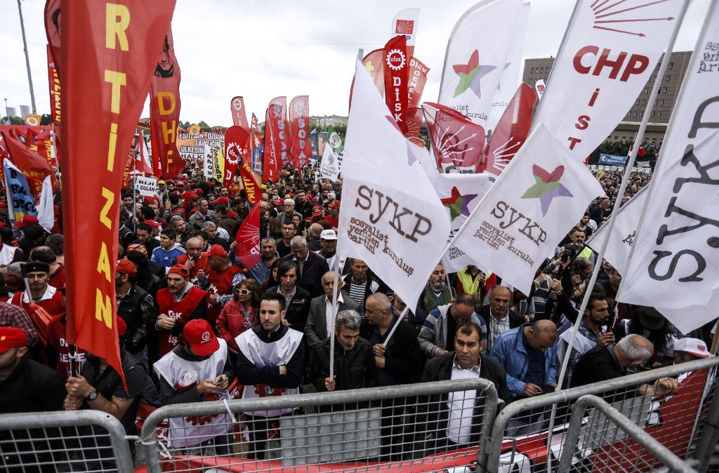 People wave flags as they gather for a May Day rally in Bakirkoy, a district of Istanbul, on May 1, 2016.  Turkish police on clamped down on unauthorised protests during a tense May Day in Istanbul, using tear gas and water cannon against demonstrators and imposing a heavy security blanket on the city. / AFP PHOTO / BULENT KILIC