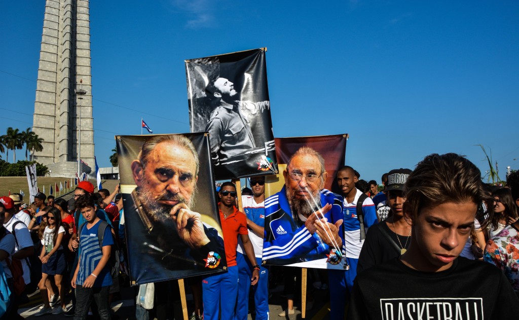 People display images of Cuban former president Fidel Castro during the May Day parade at Revolution Square in Havana, on May 1, 2016. / AFP PHOTO / JORGE BELTRAN