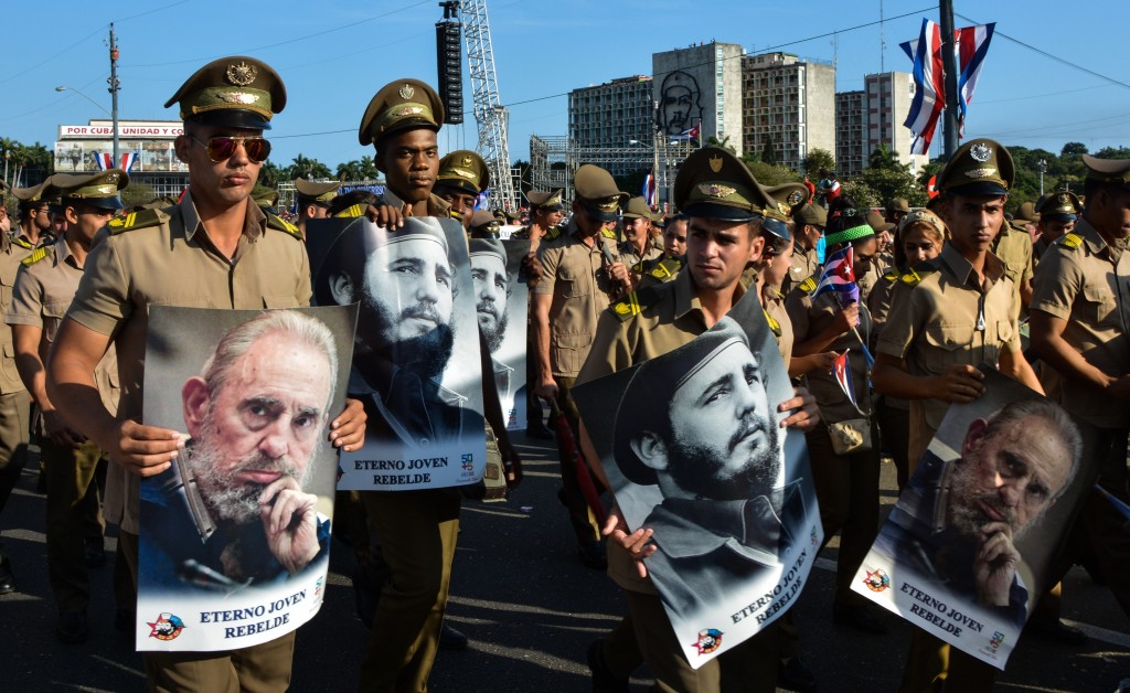 People display images of Cuban former president Fidel Castro during the May Day parade at Revolution Square in Havana, on May 1, 2016. / AFP PHOTO / JORGE BELTRAN