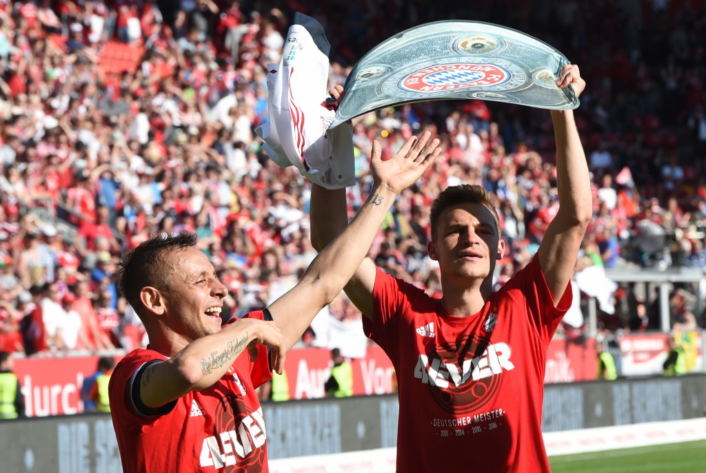 Bayern Munich's Brazilian defender Rafinha (L) and Bayern Munich's midfielder Joshua Kimmich (R) celebrate with a paper mock up of the Bundesliga trophy after the German first division Bundesliga football match between FC Ingolstadt 04 and FC Bayern Munich, at the Audi Sportpark in Ingolstadt, southern Germany, on May 7, 2016. / AFP PHOTO / CHRISTOF STACHE / RESTRICTIONS: DURING MATCH TIME: DFL RULES TO LIMIT THE ONLINE USAGE TO 15 PICTURES PER MATCH AND FORBID IMAGE SEQUENCES TO SIMULATE VIDEO. == RESTRICTED TO EDITORIAL USE == FOR FURTHER QUERIES PLEASE CONTACT DFL DIRECTLY AT + 49 69 650050