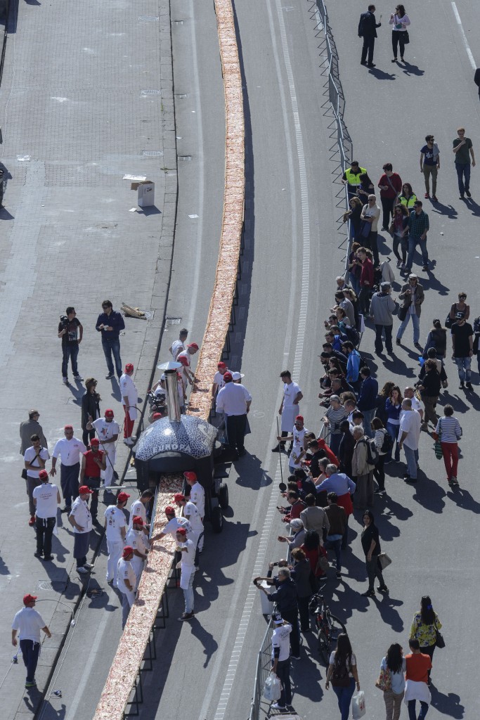 Neapolitan pizza makers attempt to make the longest pizza to break a Guinness World Record along the seafront of Naples, on May 18, 2016. For the wood-fired pizza, which measured two kilometres, they used 2,000 kg of flour, 1,600 kg of tomatoes, 2,000 kg of mozzarella, 200 litres of oil, 30kg of fresh basil. The record-breaking snack measured up at exactly 1,853.88 metres (6,082 feet), smashing the previous record of 1,595.45 metres (5,234 feet) set at last year's World Expo in Milan, Italy's food and agriculture board Coldiretti said. / AFP PHOTO / Mario LAPORTA