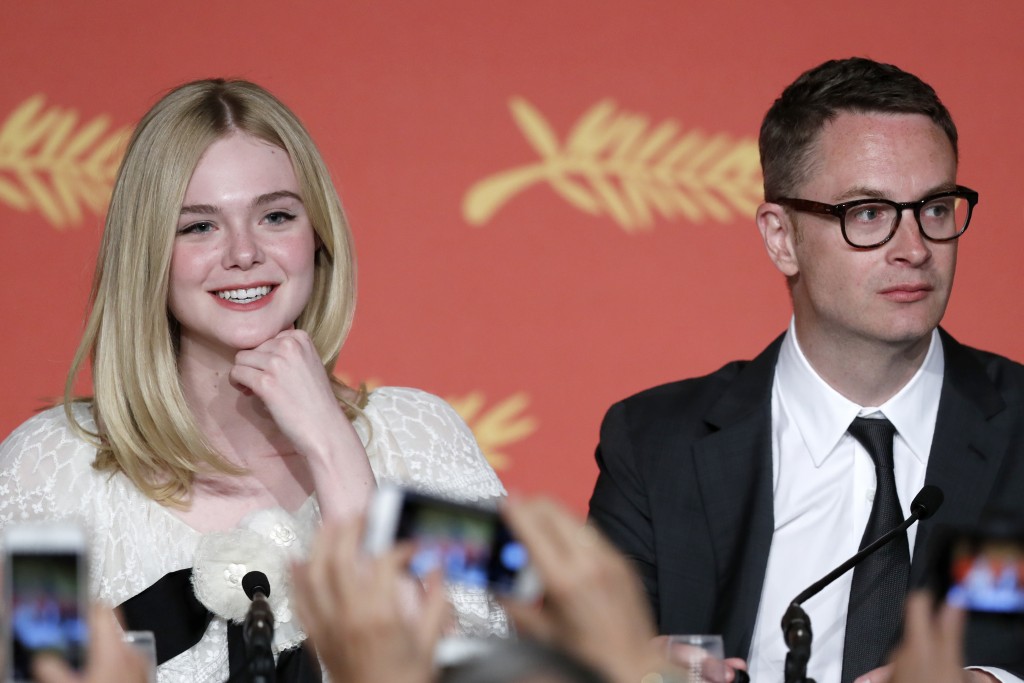 US actress Elle Fanning (L) and Danish director Nicolas Winding Refn pose for journalists as they arrive to hold on May 20, 2016 a press conference for the film "The Neon Demon" at the 69th Cannes Film Festival in Cannes, southern France. / AFP PHOTO / Laurent EMMANUEL