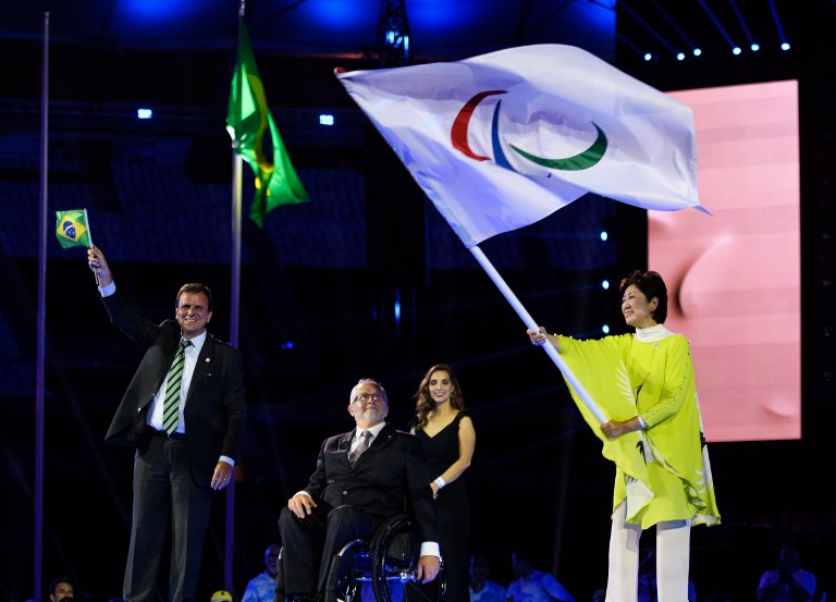 Rio de Janeiro Mayor Eduardo Paes applauds as IPC President Sir Philip Craven hands the Paralympic flag to Tokyo Governor Yuriko Koike during the closing ceremony of the Rio 2016 Paralympic Games at the Maracana Stadium in Rio de Janeiro, Brazil on September 18, 2016. Handout photo by Thomas Lovelock for OIS/IOC via AFP. RESTRICTED TO EDITORIAL USE. / AFP PHOTO / Thomas Lovelock for IOS/IOC / RESTRICTED TO EDITORIAL USE.