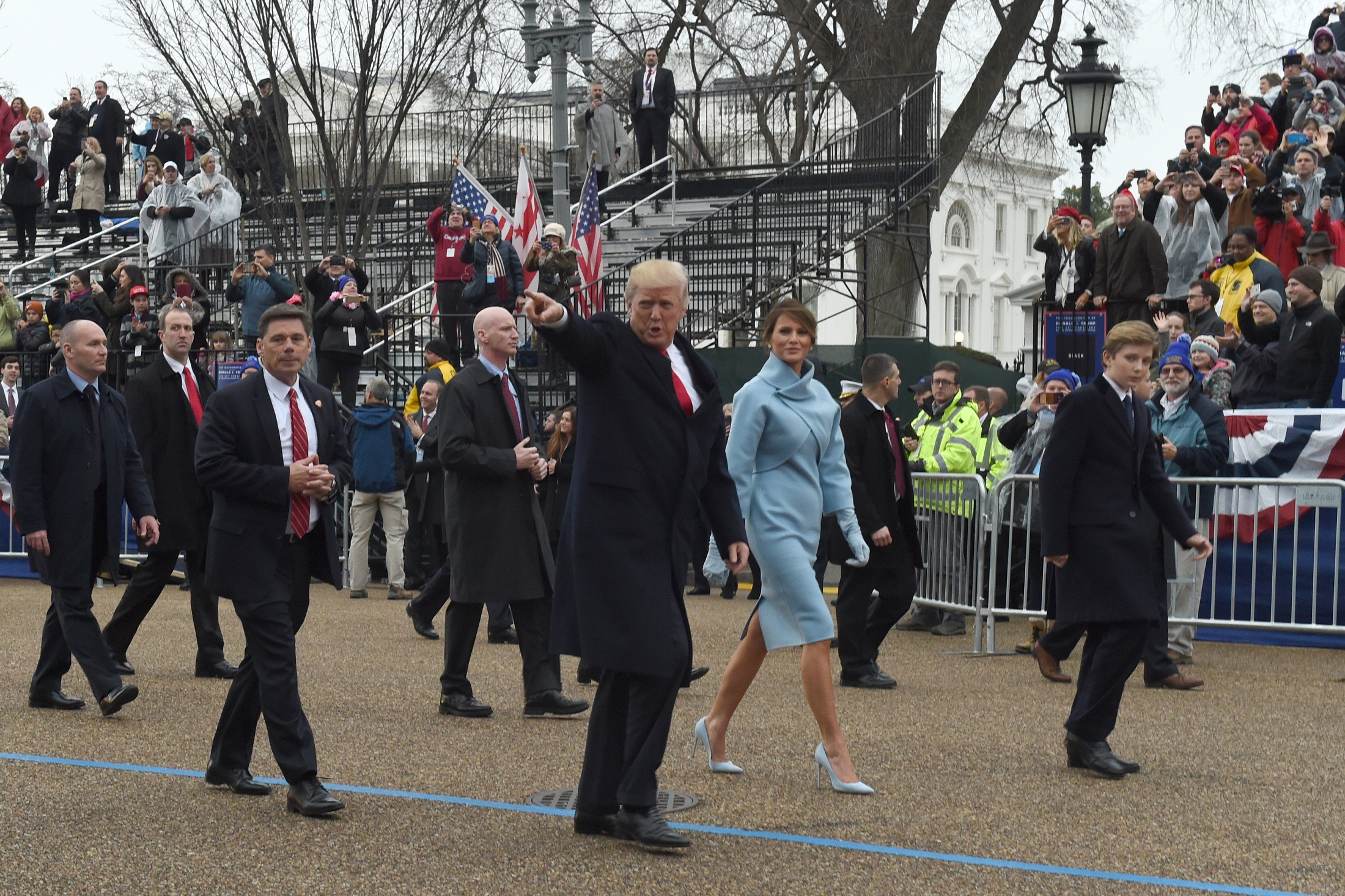 US President Donald Trump walks his son Barron (R) and wife Melania surrounded by Secret Service officers at the White House as the presidential inaugural parade winds through the nation's capital on January 20, 2017 in Washington, DC. / AFP PHOTO / Timothy A. CLARY