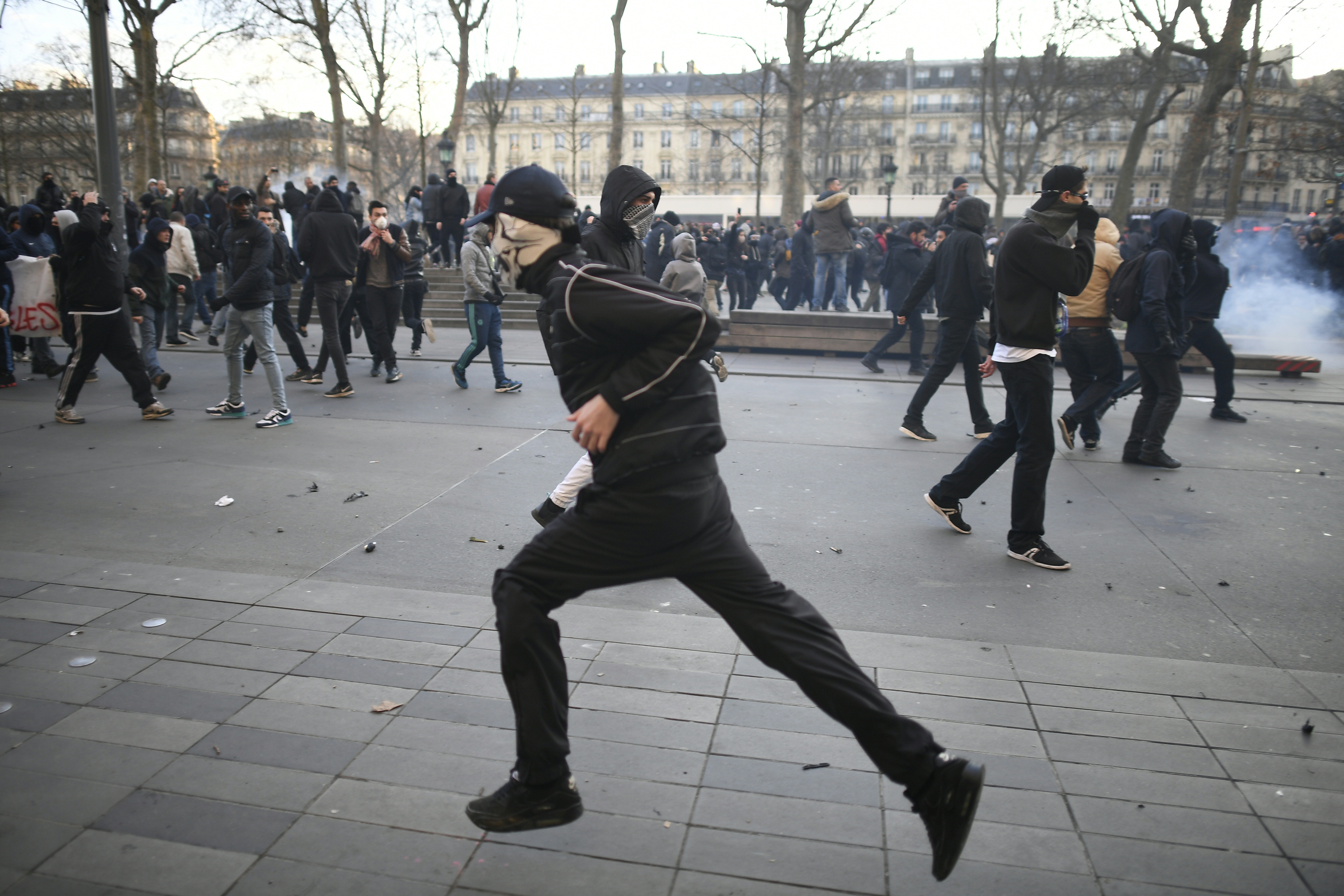 A person runs during a demonstration against police brutality on February 18, 2017 on the place de la Republique in Paris, following the alleged rape of a black youth, identified only as Theo, with a police baton, an incident that has sparked 10 nights of rioting and more than 200 arrests. The injuries sustained by Theo during a stop-and-search operation on February 2 in the suburb of Aulnay-sous-Bois, has revived long-simmering frustrations over policing in immigrant communities, where young men accuse the police of repeatedly targeting them in aggressive stop-and-search operations and using excessive force during arrests.  / AFP PHOTO / Lionel BONAVENTURE