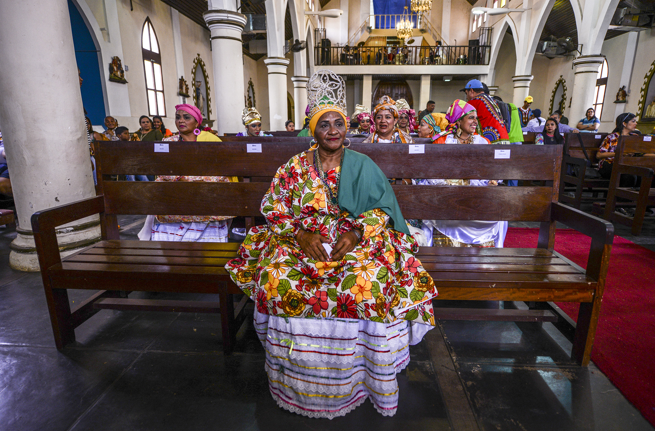 Women dressed as "madamas" attend a mass before the beginning of the Carnival in El Callao, in Bolivar state, Venezuela on February 26, 2017.  El Callao's carnival was recently named Unesco's Intangible Cultural Heritage of Humanity and is led by the madamas, the pillars of Callaoense identity representing Antillean matrons considered the communicators of values, who dance and wear colourful dresses. / AFP PHOTO / JUAN BARRETO