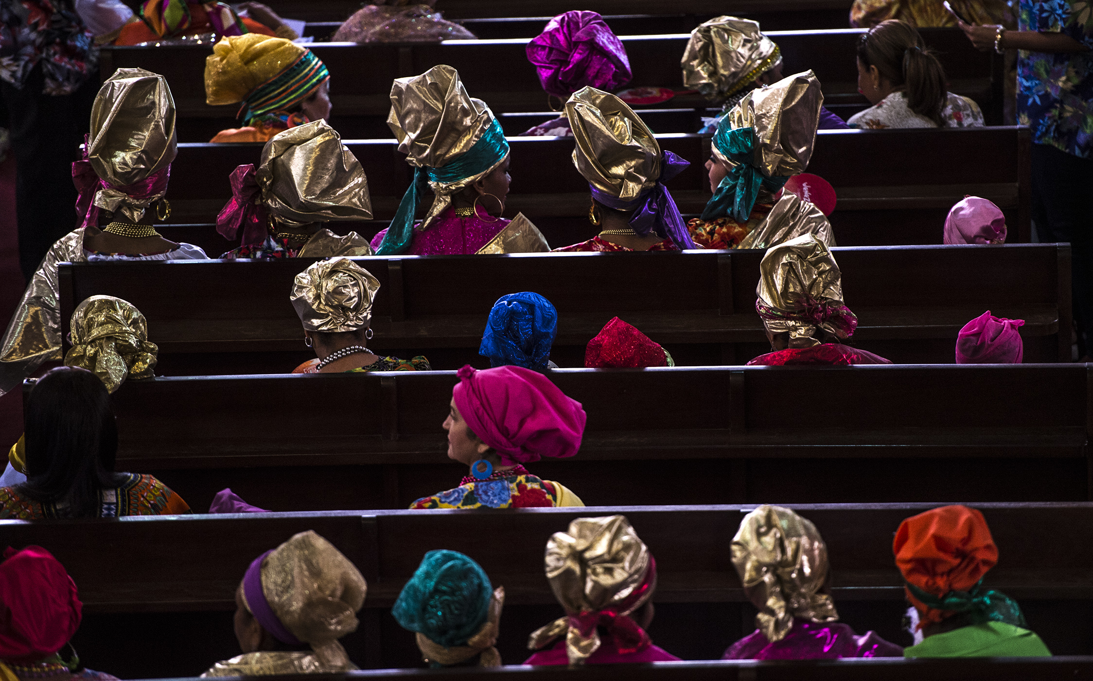 Women dressed as "madamas" attend a mass before the beginning of the Carnival in El Callao, Bolivar state, Venezuela on February 26, 2017.  El Callao's carnival was recently named Unesco's Intangible Cultural Heritage of Humanity and is led by the madamas, the pillars of Callaoense identity representing Antillean matrons considered the communicators of values, who dance and wear colourful dresses. / AFP PHOTO / JUAN BARRETO