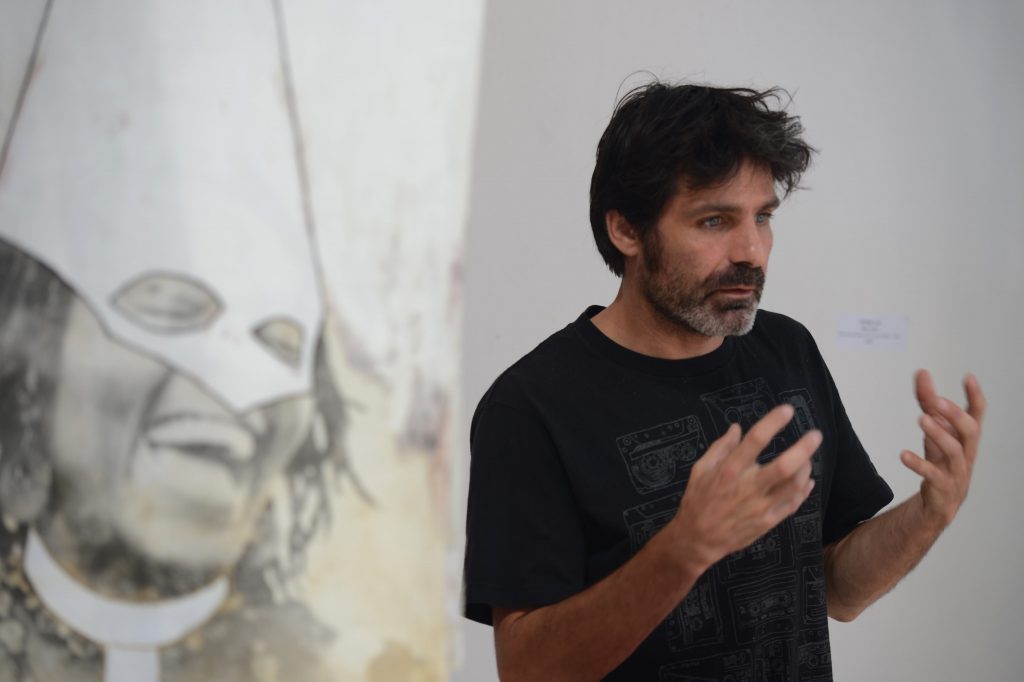 French photographer Nicolas Guyot speaks next to one of his works during his exhibition 'Imagenes de lo insondable" (Images of the unfathomable) in Tegucigalpa on March 21, 2017.   Guyot's work includes images taken in Syria, Congo and Nepal, among other scenarios, processed using film techniques and silver bromide development. / AFP PHOTO / ORLANDO SIERRA