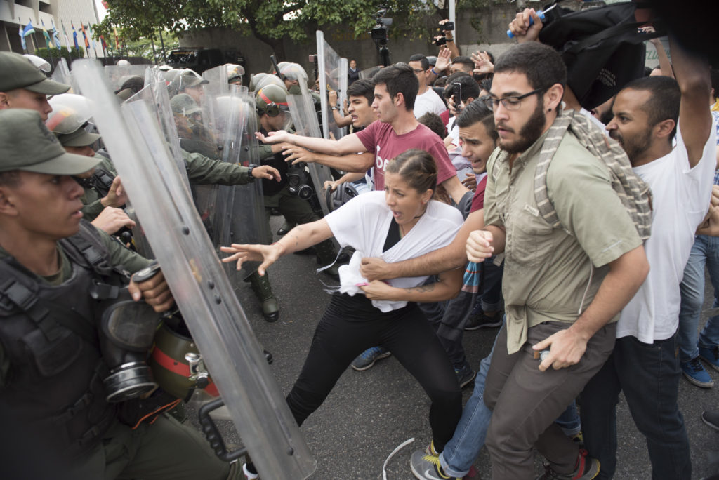 Venezuelan opposition activists scuffle with National Guard personnel in riot gear during a protest in front of the Supreme Court in Caracas on March 31, 2017. Venezuela's attorney general Luisa Ortega surprisingly broke ranks with President Nicolas Maduro on Friday, condemning recent Supreme Court rulings that consolidated the socialist president's power as a "rupture of constitutional order." / AFP PHOTO / STR