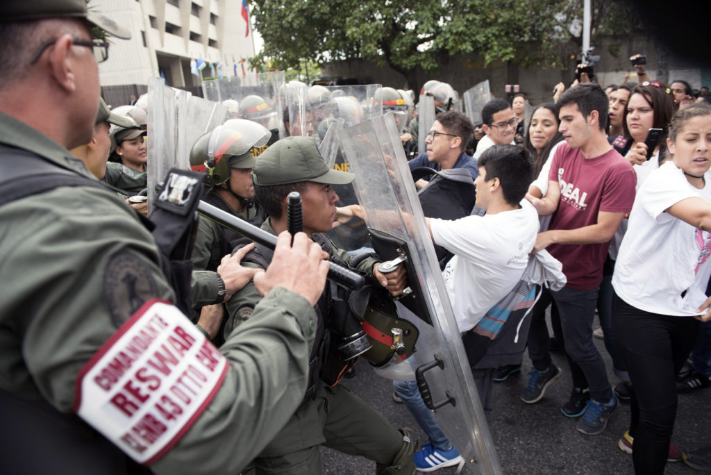Venezuelan opposition activists scuffle with National Guard personnel in riot gear during a protest in front of the Supreme Court in Caracas on March 31, 2017. Venezuela's attorney general Luisa Ortega surprisingly broke ranks with President Nicolas Maduro on Friday, condemning recent Supreme Court rulings that consolidated the socialist president's power as a "rupture of constitutional order." / AFP PHOTO / STR